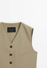 Gilet beige sans manches avec col en V et trois boutons foncés sur le devant, fabriqué en tissu texturé.