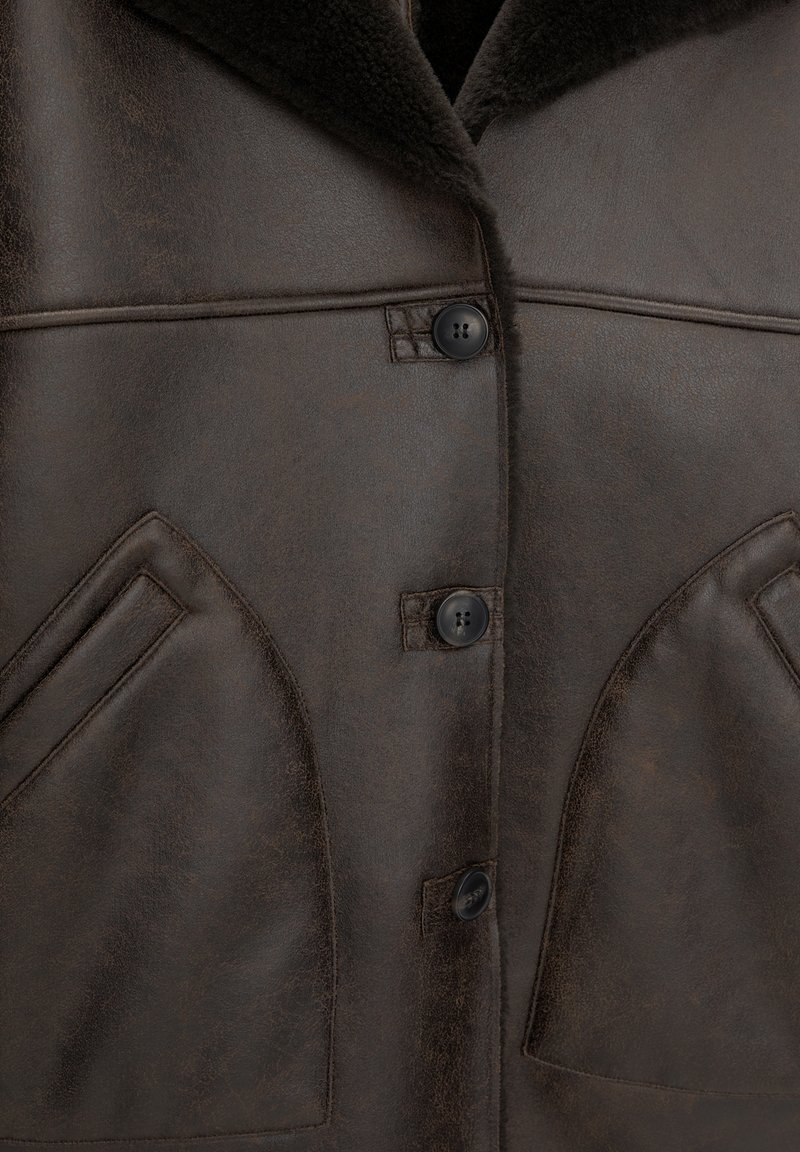 Braune Lederjacke mit weichem Kragen, Knopfverschluss vorne und zwei schrägen Taschen mit dezenten Steppdetails.