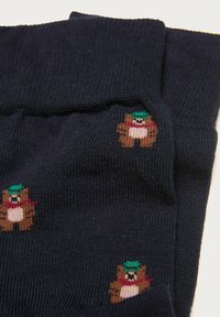 Marineblaue Socken aus geripptem Strickstoff, verziert mit kleinen, bunten Bärenmotiven, die Schals und Hüte tragen.