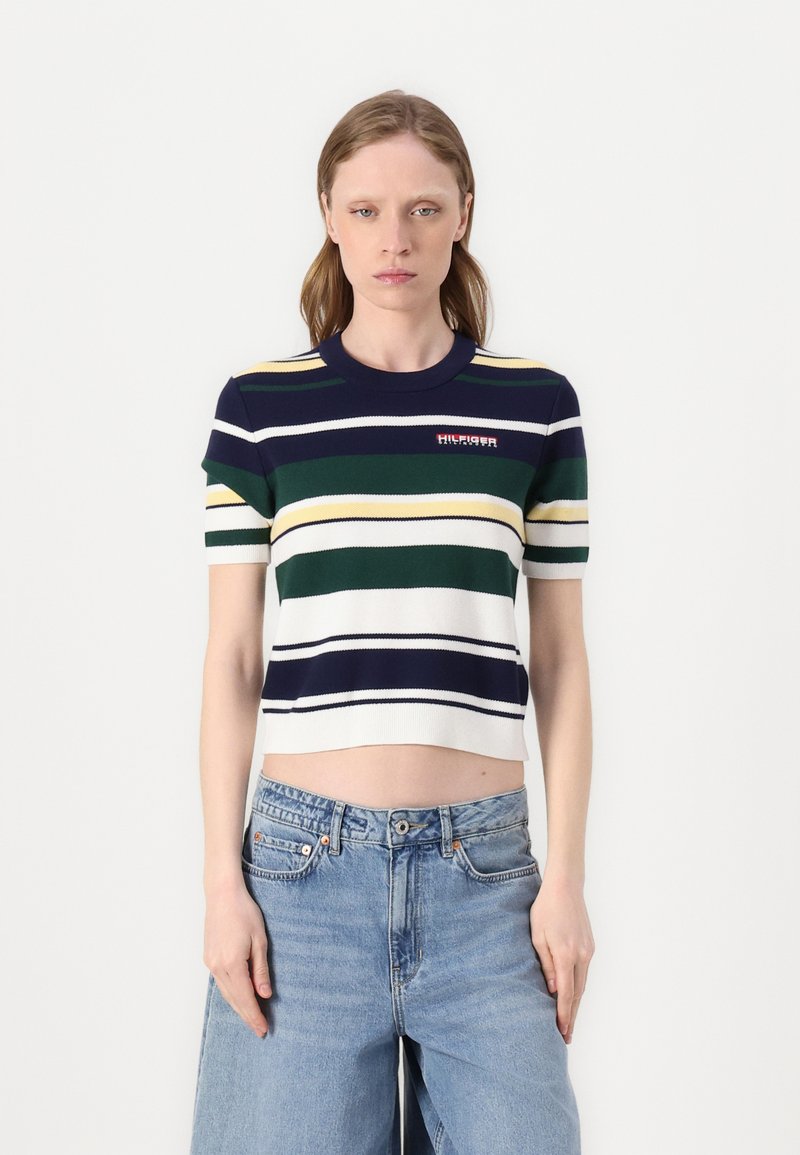 Top corto a righe in maglia, di colore blu navy, verde e bianco, con maniche corte e scollo rotondo. Dettaglio del logo in rosso sulla parte anteriore.