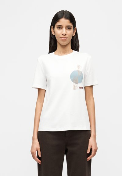 T-shirt en coton blanc présentant un motif graphique avec un cercle bleu et des traits de pinceau abstraits. Col rond, manches courtes, coupe décontractée.
