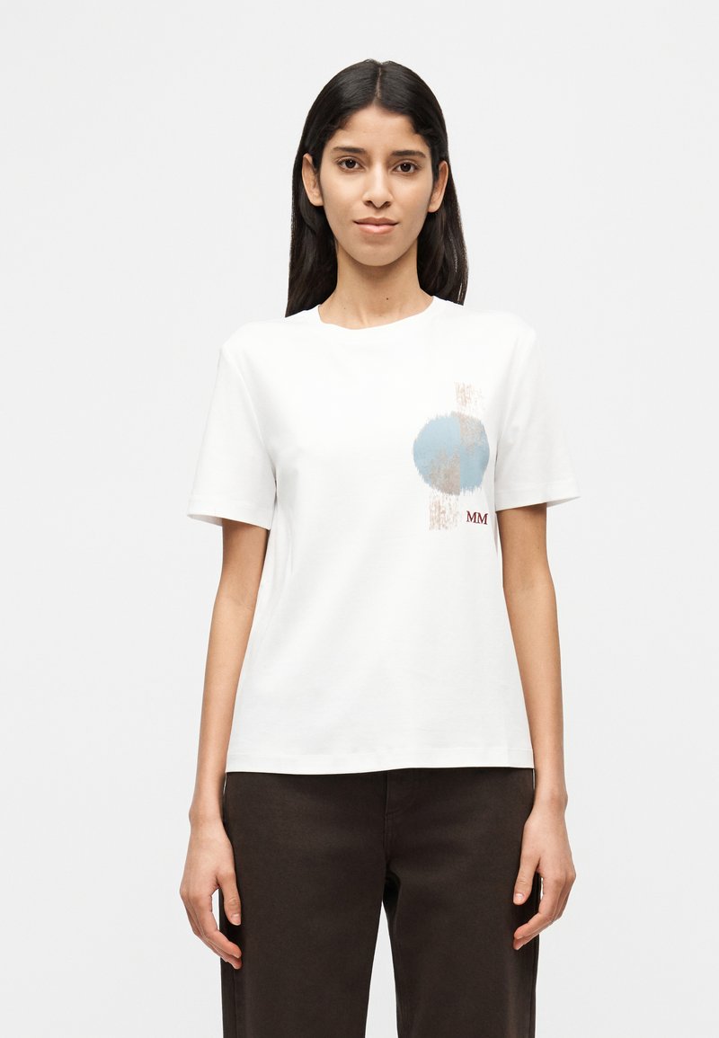 Λευκό βαμβακερό T-shirt με γραφικό σχέδιο που περιλαμβάνει έναν μπλε κύκλο και αφηρημένες πινελιές. Λαιμόκοψη γύρω, κοντά μανίκια, άνετη εφαρμογή.