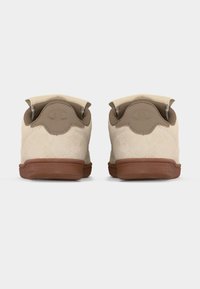 Ζευγάρι μπεζ σουέντ αθλητικά παπούτσια με καφέ ταμπελάκια στη φτέρνα και σόλες από καουτσούκ, φωτογραφημένα από πίσω πάνω σε απλό λευκό φόντο.