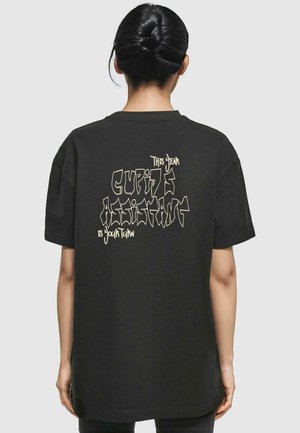 Black oversized t-shirt made of cotton, featuring a textured graphic design in light beige text: "This Dear Cupid's Assistant Is Your Turn" on the back.