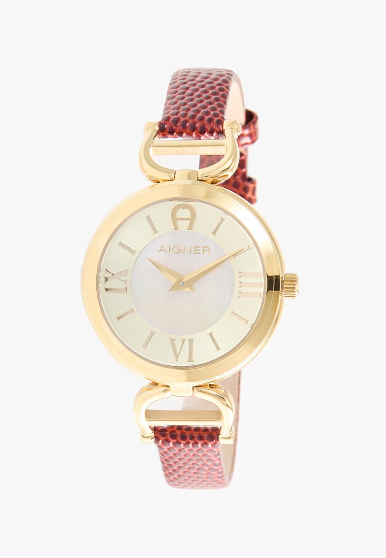 Montre-bracelet ronde dorée avec des chiffres romains, cadran en mère perle légère et bracelet en cuir marron texturé. Nom de la marque "Aigner" sur le cadran.
