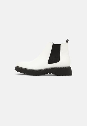Bottine Chelsea en cuir blanc avec panneau latéral élastique noir, semelle épaisse noire et languette à l'arrière.