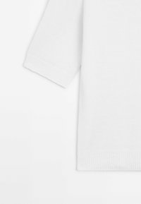 Weißes Strickoberteil mit kurzen Ärmeln, ausgestattet mit einer weichen Textur und gerippten Bündchen. Einfaches, minimalistisches Design ohne zusätzliche Muster oder Akzente.