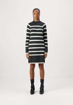 Robe en tricot avec des rayures noir et blanc, col rond, manches longues, texture côtelée et fentes sur les côtés à l'ourlet.