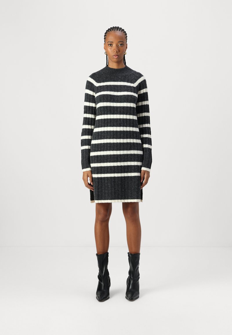 Robe en tricot avec des rayures noir et blanc, col rond, manches longues, texture côtelée et fentes sur les côtés à l'ourlet.