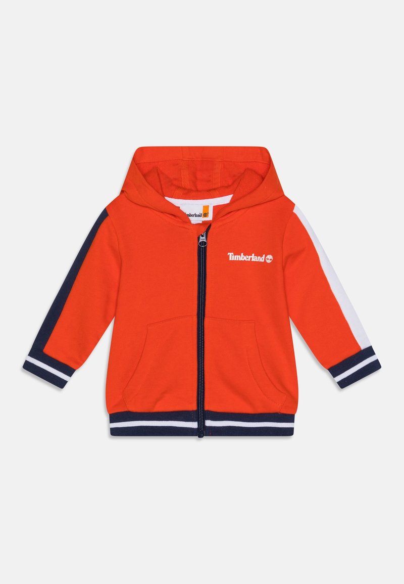 Sweat à capuche zippé pour tout-petit rouge avec capuche, rayures bleu marine et blanches sur les manches et l'ourlet, poches avant, et logo Timberland blanc sur la poitrine.