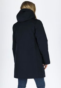 Cappotto impermeabile blu navy con cappuccio. Presenta maniche lunghe, tasche laterali e una linea dritta, realizzato in tessuto morbido e resistente.