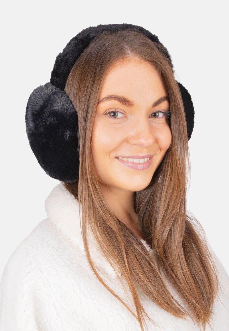 Cache-oreilles en fausse fourrure noire de forme ronde, avec un rembourrage épais et une surface texturée, portés par une personne aux longs cheveux bruns.