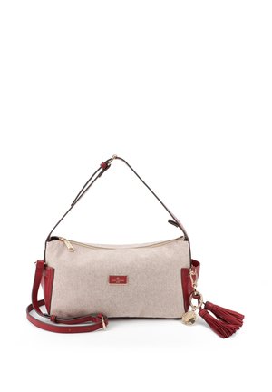 Borsa in tessuto beige con rifiniture in pelle rossa, tracolla regolabile, cerniera dorata e portachiavi con nappina rossa appeso al lato.