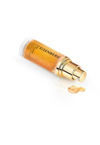 Sérum de soins Eisenberg dans un flacon transparent avec une pompe dorée. Contient un liquide ambre léger, accompagné d'une goutte à la surface.