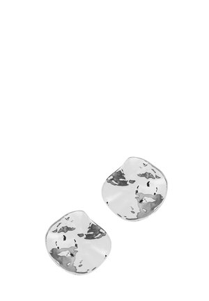 Deux boucles d'oreilles clous en métal argenté brillant de forme irrégulière avec une texture légèrement martelée sur fond blanc.