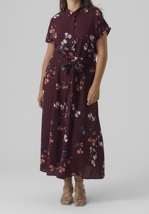 Frau trägt ein kastanienbraunes Midikleid mit floralem Muster, kurzen Ärmeln, Knopfleiste, gebundenem Taillenband und beigen Riemchensandalen.