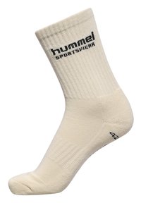Beige bomulds sportsokken med ribbet tekstur og sort "hummel SPORTSWEAR" logo. Midt på læggen længde med forstærkede hæl og tå sektioner.