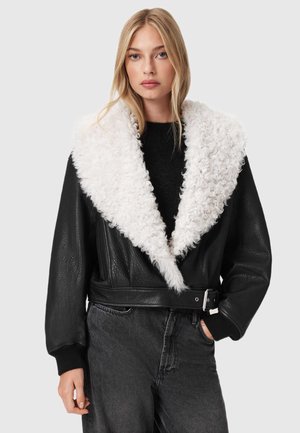 Svart läderjacka med vit fuskpälskrage. Har en kortad design, bälte i midjan och textil med texturerad yta samt ribbade ärmslut.