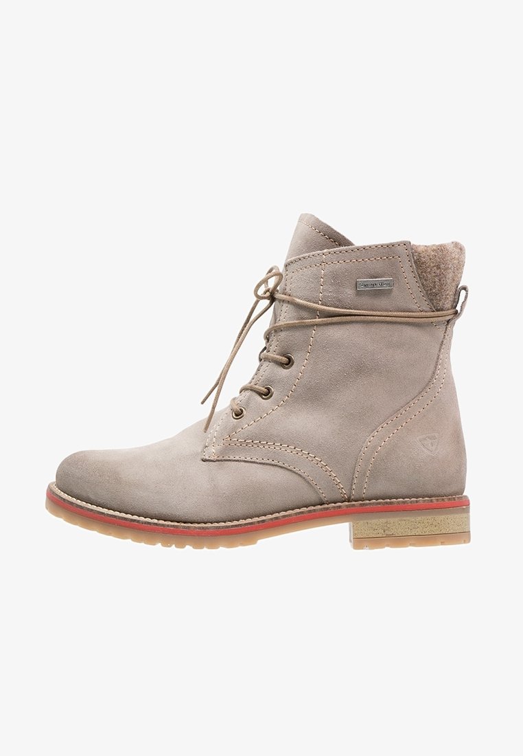 Bottine beige en daim avec laçage à l'avant, bordure rouge sur la semelle, col rembourré et petit talon en bois empilé.