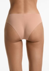 Lichte, naadloze slipjes van een zacht beige materiaal, met een laaghangend ontwerp en een gladde, matte textuur voor comfort en minimale zichtbaarheid.