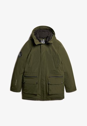 Parka acolchada de color verde oliva con capucha, cuenta con dos bolsillos frontales con solapa, bolsillos laterales con cremallera y un parche con el logo en la manga izquierda.