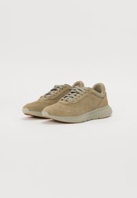 Adidași din suede de culoare maro deschis, cu un superior texturat, șireturi gri, talpă din cauciuc și detalii perforate pe laterale pentru respirabilitate.