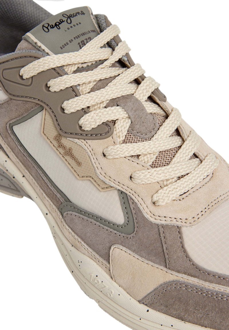 Beige en grijze sneaker van mesh en suède materialen, met getextureerde accenten, crème veters en logo op de tong, met een ronde neus en een geprofileerde zool.