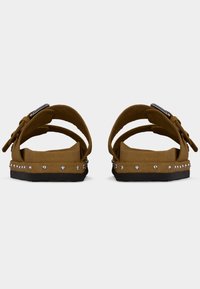 Καφέ σουέτ σανδάλια με υφή, διαθέτουν δύο ρυθμιζόμενους ιμάντες, στρογγυλεμένη μύτη και ασημένια καρφιά στην βάση.