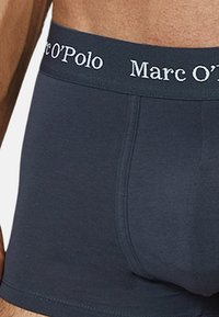 Tummansinisiä bokseritaskuja, joissa on tiukka istuvuus ja pehmeä vyötärö. Vyötärössä on kontrastivalkoisella tekstillä "Marc O'Polo".