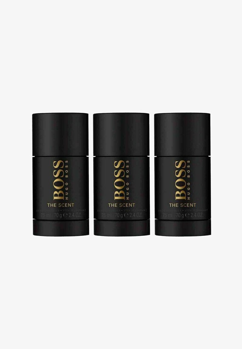 Kolme sylinterimäistä mustaa deodoranttipulloa, joissa on kultainen teksti "BOSS HUGO BOSS THE SCENT", jokainen merkitty 75 ml ja 70 g.