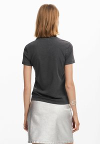 Donkergrijze katoenen T-shirt met korte mouwen, ronde halslijn en een gladde textuur, gecombineerd met een glanzende zilveren rok.