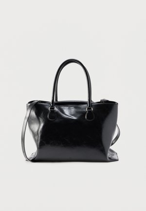 Borsa tote in pelle nera con due manici e una tracolla regolabile su uno sfondo chiaro e semplice.