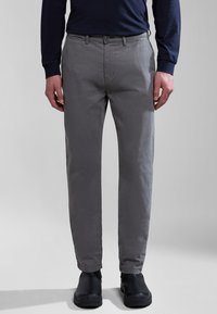 Chinos in cotone grigi con una vestibilità slim, tasche anteriori e una trama sottile. Abbinati a scarpe nere, esposti su uno sfondo neutro.