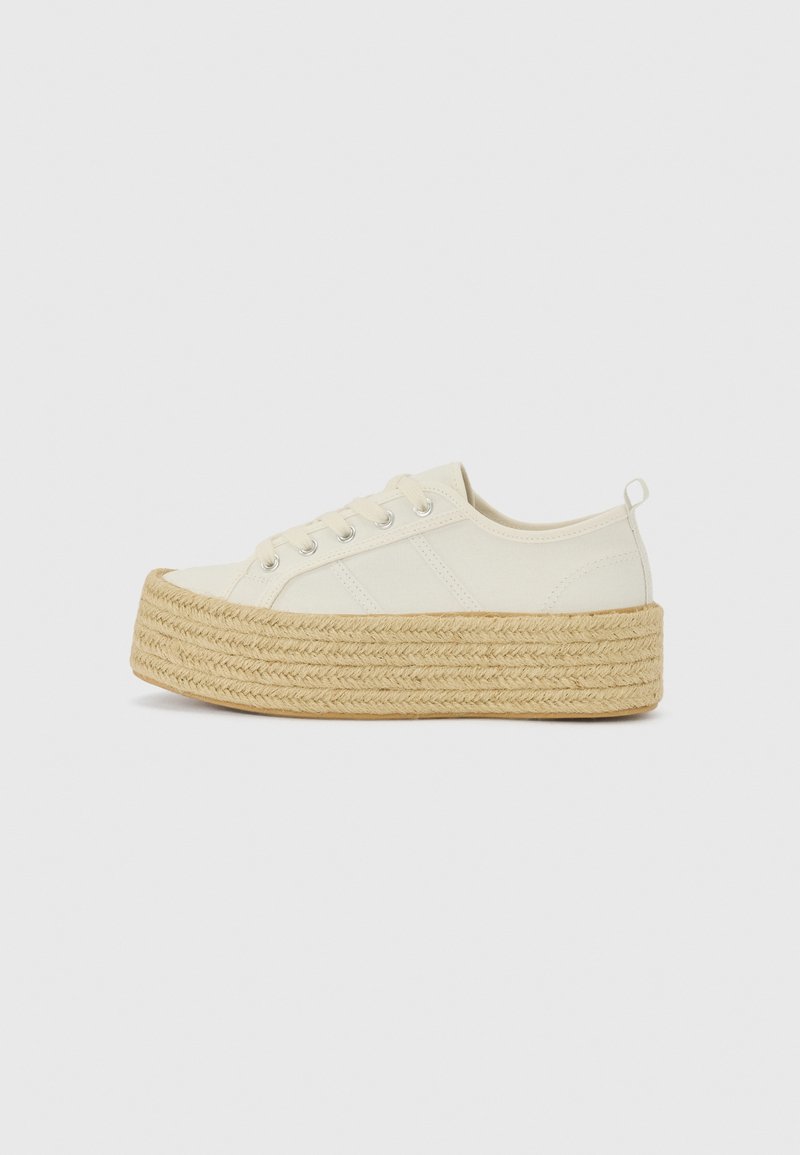 Plattform sneakers i off-white lerret med en strukturert, vevd jute såle. Har metallhull og flate snøringer. Rund tådesign.