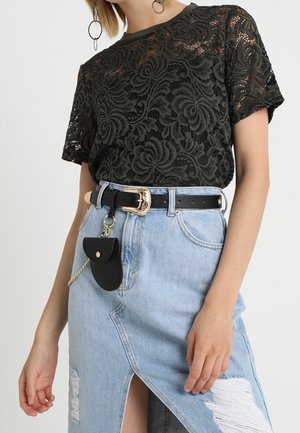 Czarna koronkowa bluzka z krótkim rękawem w połączeniu z jasnoniebieską, postrzępioną dżinsową spódnicą z przednim rozcięciem, czarnym paskiem ze złotą klamrą i małą przymocowaną saszetką.