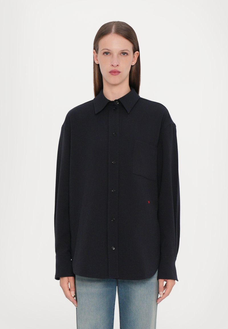 Camicia nera a maniche lunghe con colletto alla francese, taschino frontale e delicati dettagli del logo rosso, realizzata in un tessuto liscio.