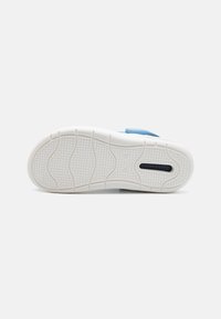 Blue shoe with a textured sole featuring wavy patterns; white rubber outsole with a smooth finish and a circular logo imprint.