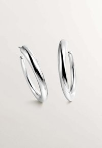 Pendientes de aro plateados con una superficie lisa y reflectante. Forma curvada con un diseño ligeramente alargado. Cierre de poste seguro.