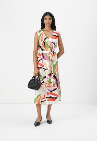 Multicolored wrap dress with a V-neckline and waist tie, featuring swirling patterns in pink, green, and black. Paired with a small black bag.
