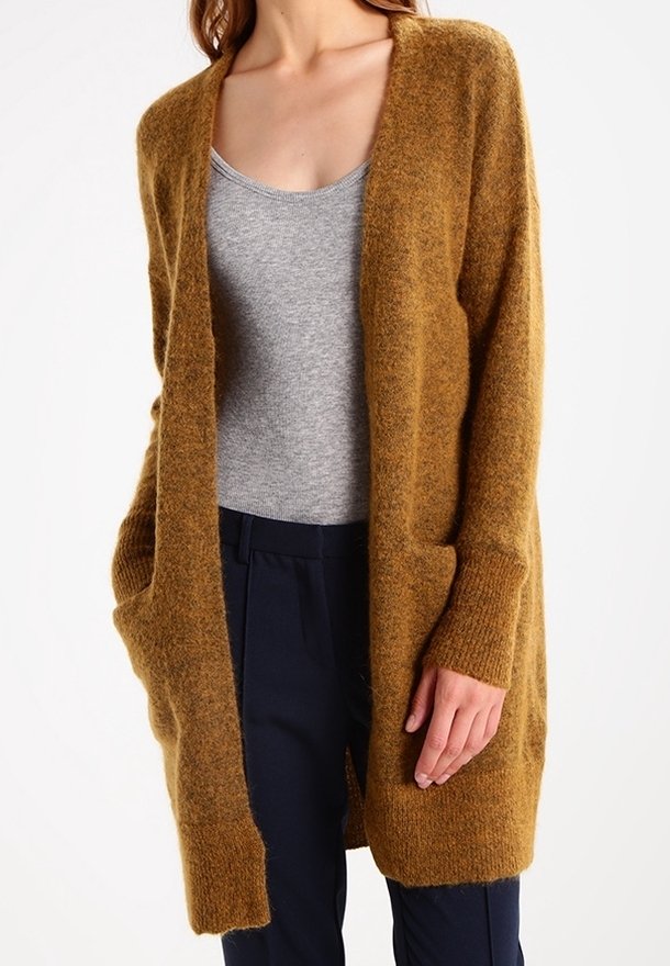 Cárdigan largo de apertura frontal en color mostaza, hecho de un material suave y peludo. Presenta dos bolsillos laterales y puños de canalé.