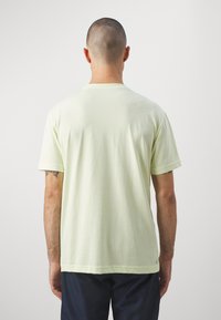 Lys grøn bomulds T-shirt med korte ærmer, rund halsudskæring og en afslappet pasform. Glat tekstur og et lille mærke ved kanten.