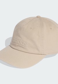 Gorra de algodón beige con visera curva, que presenta un sutil logotipo bordado en la parte frontal y ojales de ventilación en la parte superior.