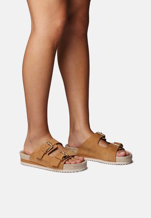 Hnedé semišové šľapky so dvoma nastaviteľnými prackami, otvorenou špičkou a textúrovanou podrážkou s gumovými detailmi.