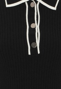 Tissu côtelé noir avec un col bordé de blanc, doté de quatre boutons argentés sur la patte de boutonnage. La texture est douce et ajustée.