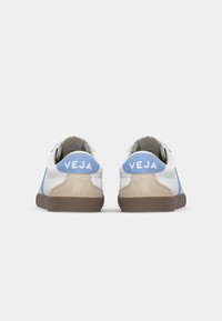 Sneakers con pelle bianca e accenti di suede blu chiaro, suola in gomma marrone e logo "VEJA" sul tallone, caratterizzati da un design atletico classico.