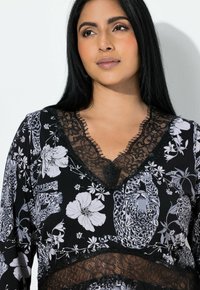 Sort top med blomsterprint og grå leopardgrafik, blondekant langs halsudskæringen og en afslappet pasform.