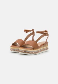 Ruskeat nahka wedge-sandaalit, joissa on ristikkäiset hihnat, avotossumuotoilu ja punottu espadrille-tyylinen pohja, jossa on useita värillisiä raitoja.