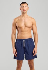 Shorts de bain bleu marine avec taille élastique et cordon blanc, en tissu lisse et léger, dotés de poches latérales.
