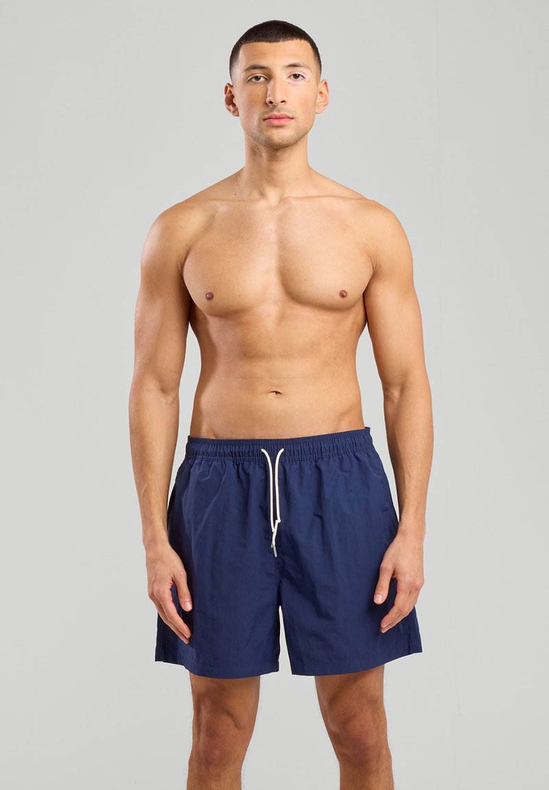 Shorts de bain bleu marine avec taille élastique et cordon blanc, en tissu lisse et léger, dotés de poches latérales.