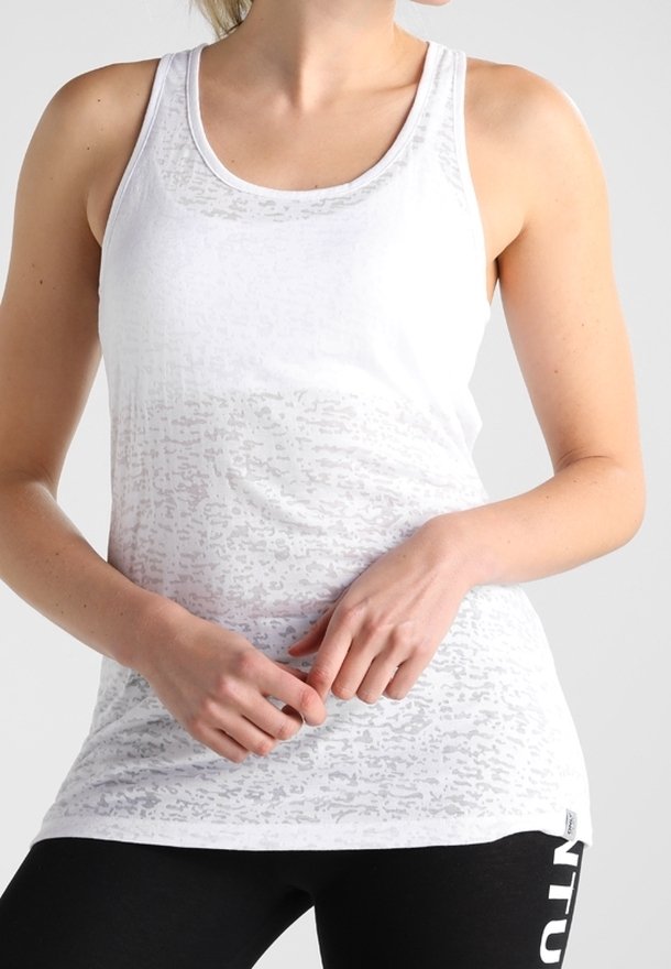 Biały top na ramiączkach o teksturowanym, półprzezroczystym wykończeniu. Posiada dekolt w kształcie litery U i szerokie otwory na ramiona, w połączeniu z czarnymi legginsami.